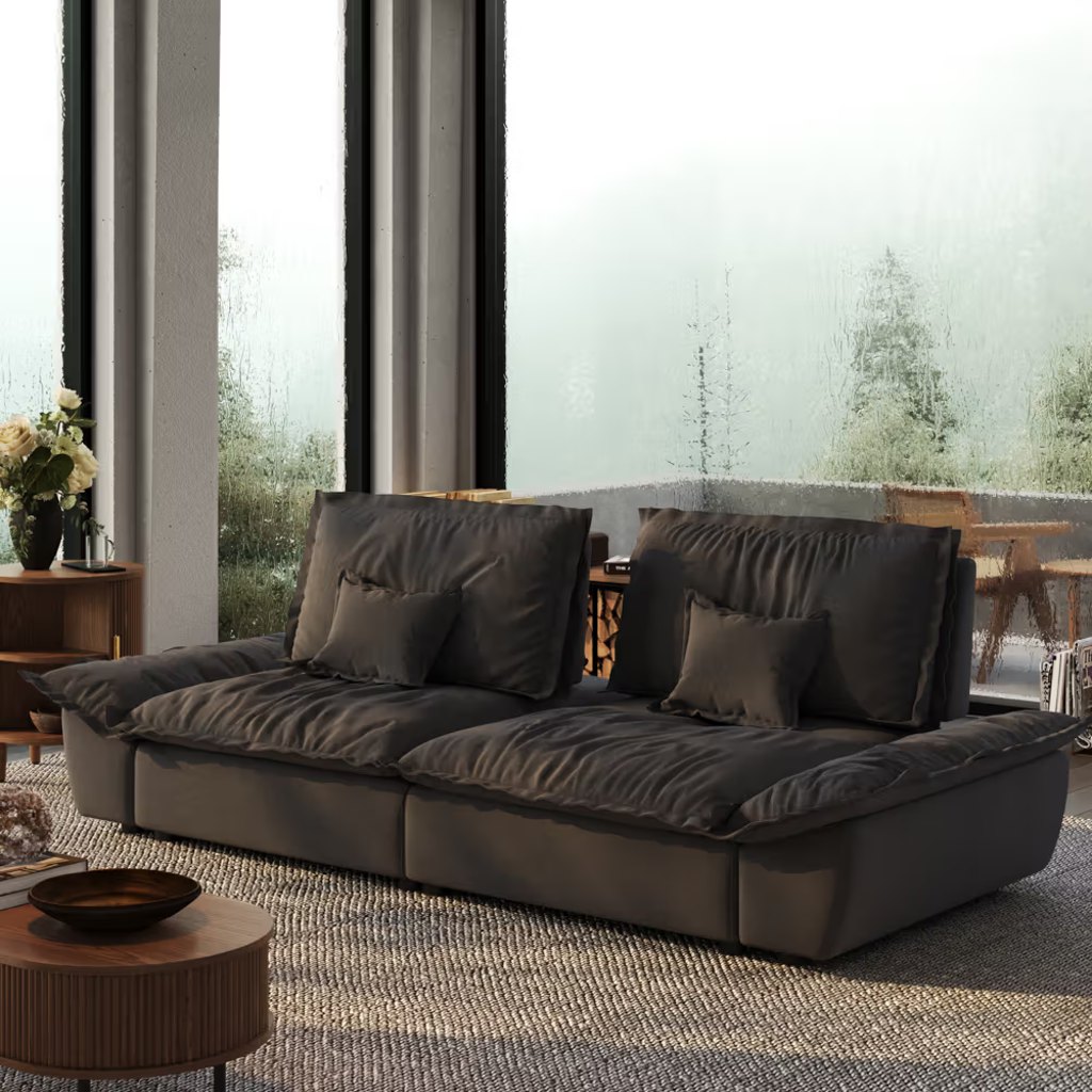 Dark gray low-profile sofa with wide cushioned seats in a modern living room with floor-to-ceiling windows.