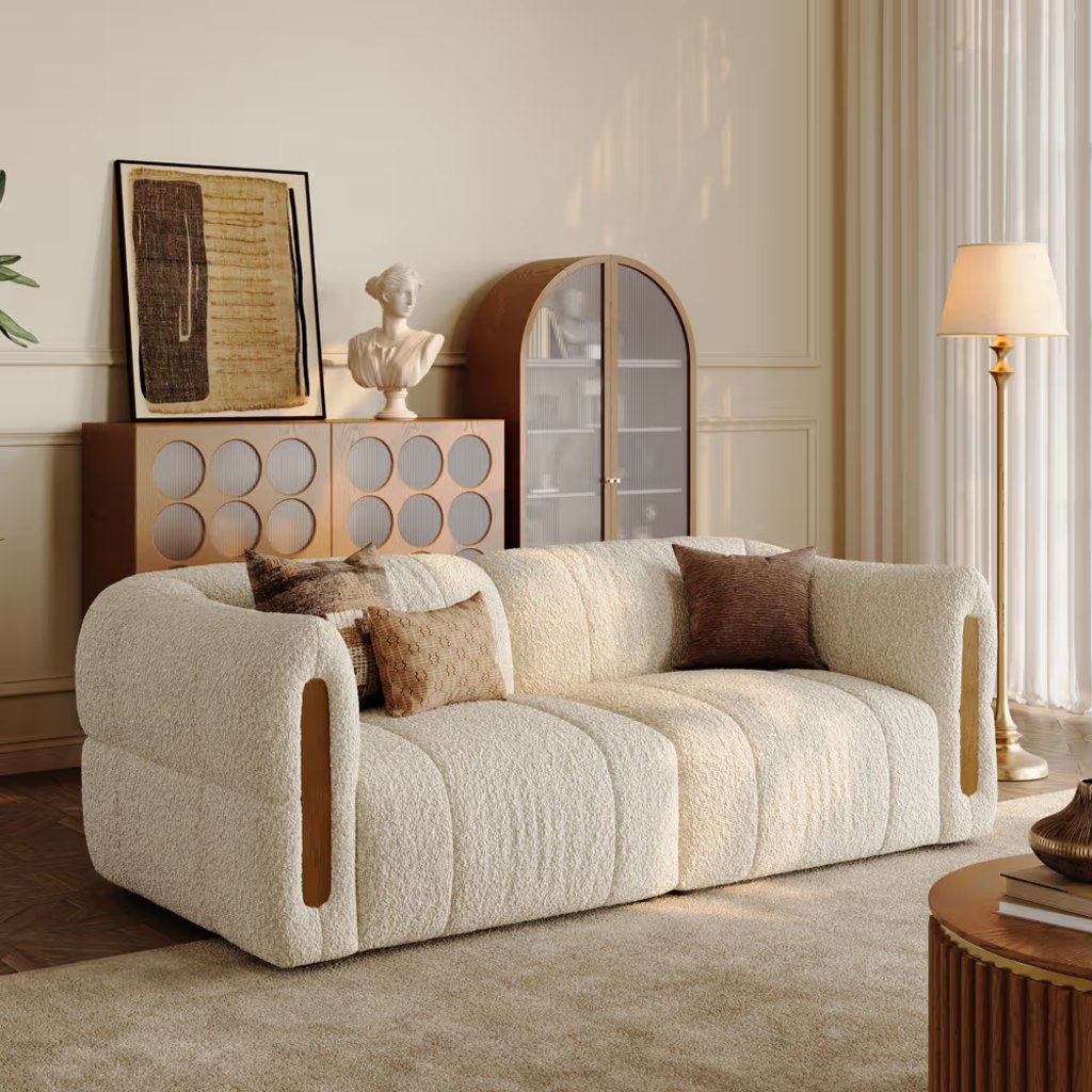 Cream bouclé deep-seat sofa with rounded arms and wood accents in a warm, elegant living room.