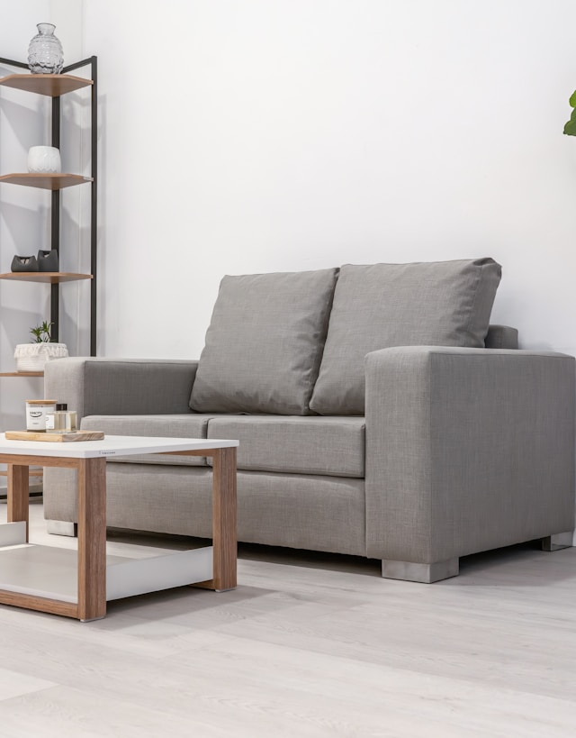 A gray loveseat and coffee table in a room