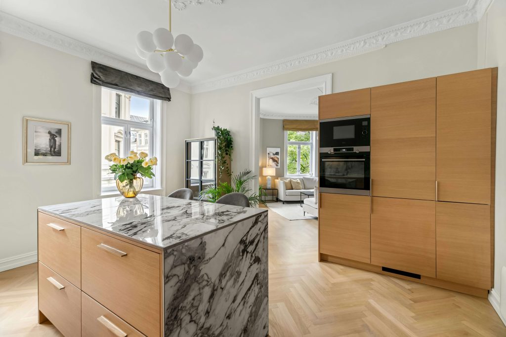 A kitchen with a marble island and wooden cabinets