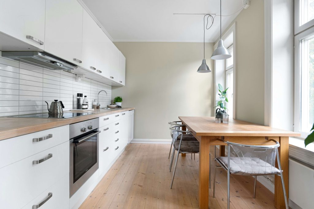 A kitchen with white cabinets and a wooden table