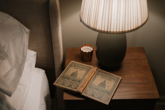 Open book on bedside table with lamp