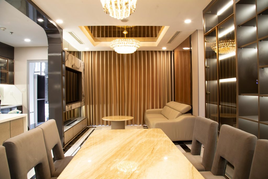 A modern dining room with a large table and chairs, parquet floor, and natural light.