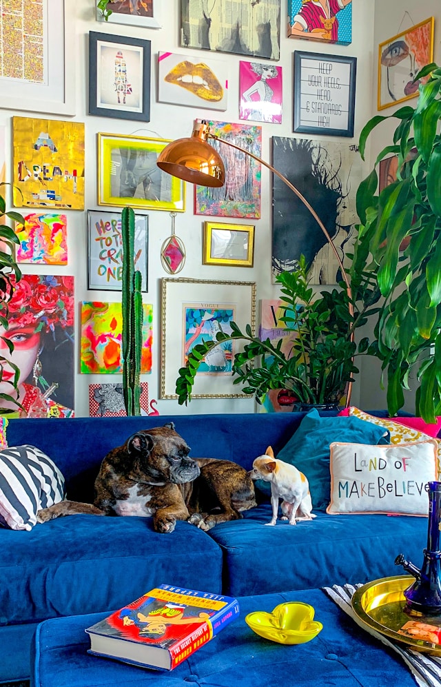 two dogs sitting on a blue loveseat couch in a living room