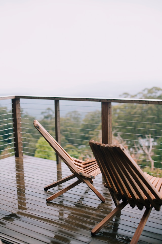 two wooden folding lounge chairs on a balcony deck after rain