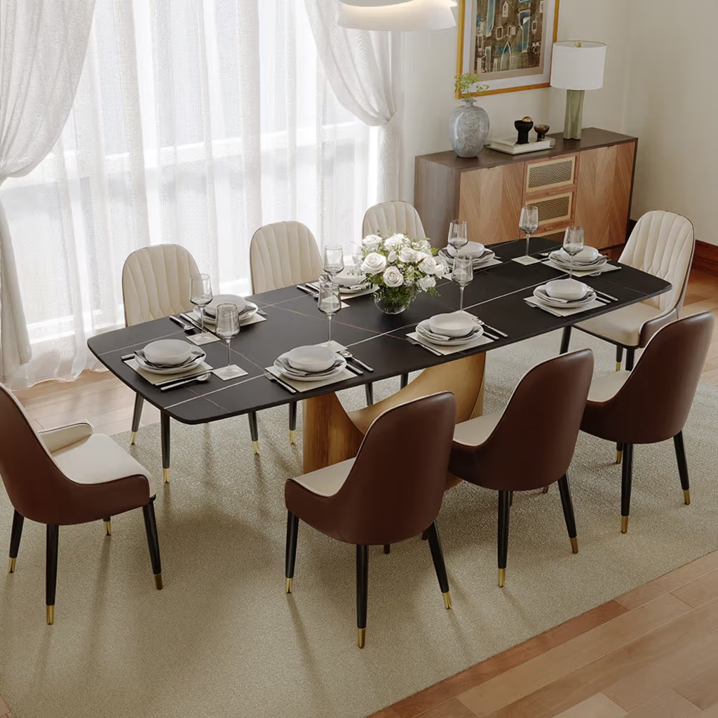 Black rectangular dining table set for eight with mixed brown and cream chairs in a bright modern dining room.