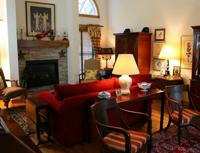 Classic living room with a red loveseat and a brown wooden console table beside it, styled with a lamp and decor — good for showing console-table styling.