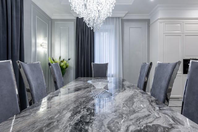 Contemporary dining room with a marble-style stone dining table, comfortable chairs, and soft natural light