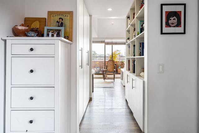 Modern hallway with built-in storage cabinets and wooden floor leading to a bright living area