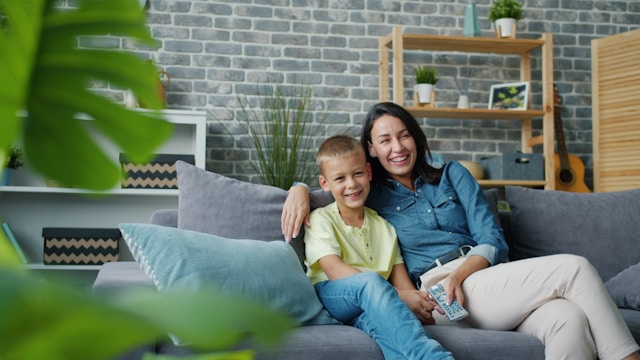 Mother and son smiling together on a couch in a bright living room