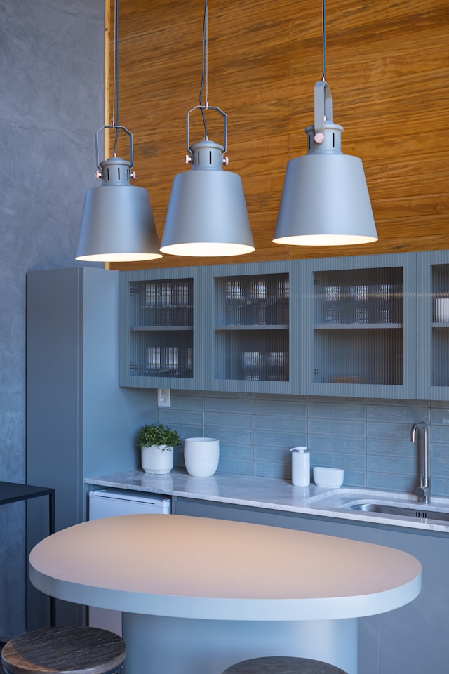 Three modern pendant lights hang over a kitchen island.