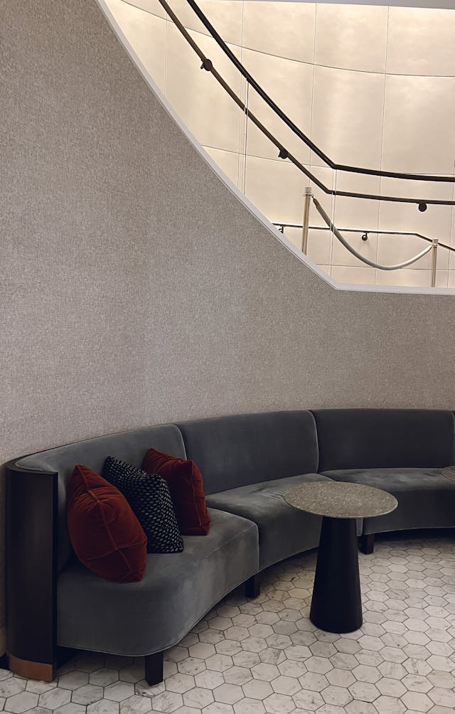 Warm-toned lounge with curved sofa and round table