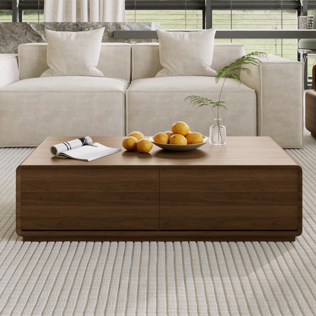 Rectangular walnut coffee table with hidden storage drawers in front of a cream sofa in a modern living room.