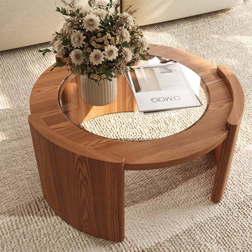 Round wood and glass coffee table with flowers and books in a bright living room.