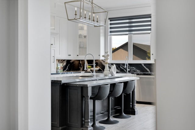 modern kitchen island with black base and curved bar stools under marble countertop