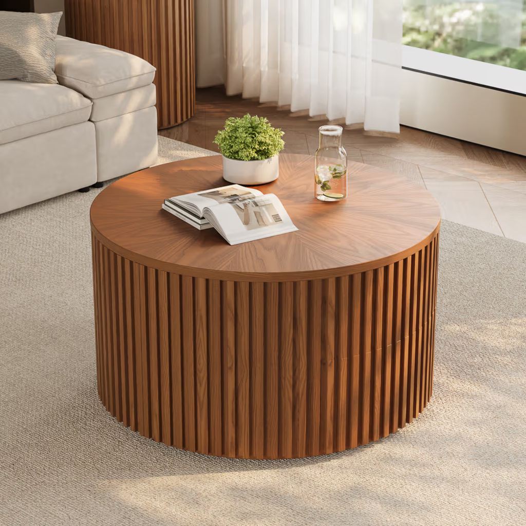 Round walnut drum coffee table with a fluted wood base in a bright modern living room.