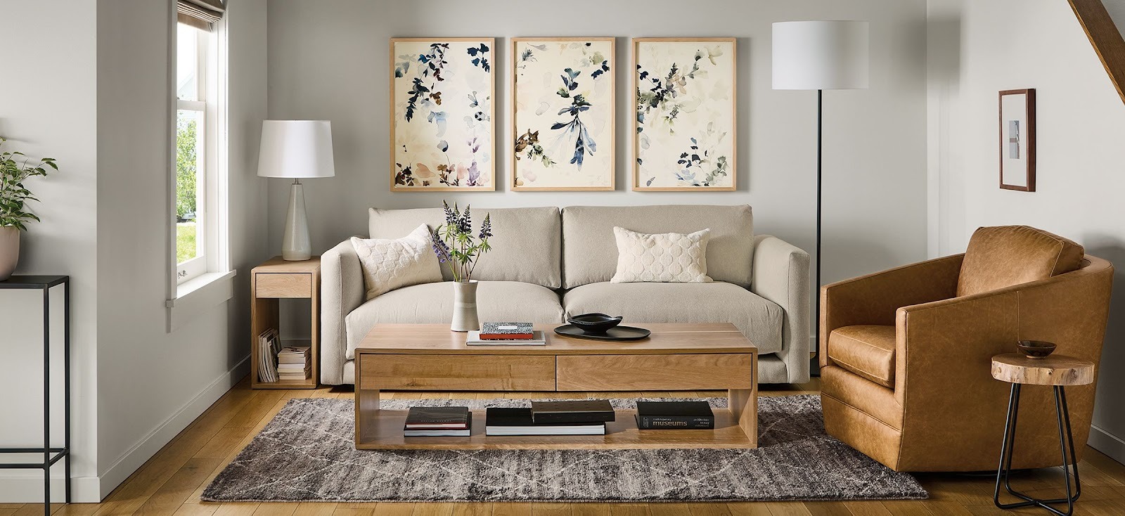 Bright neutral living room with a cream sofa, tan armchair and wooden coffee table.