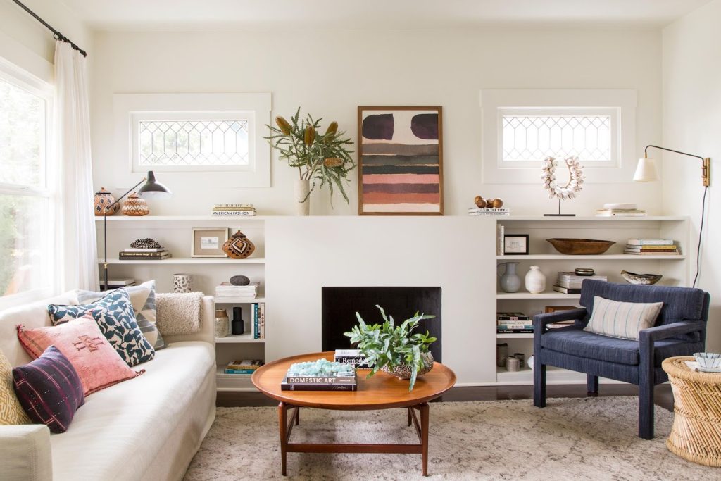 Compact living room with a white sofa, navy armchair, built-in shelves and round coffee table.
