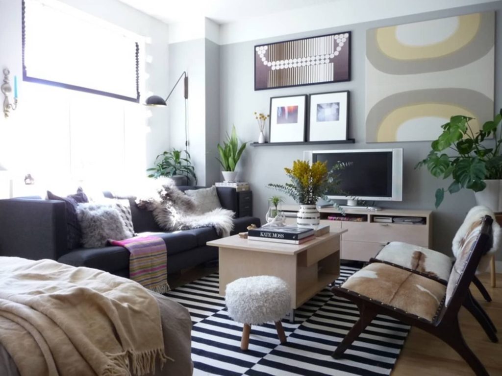 Colorful modern living room with a dark sectional sofa, striped rug and gallery wall above the TV.