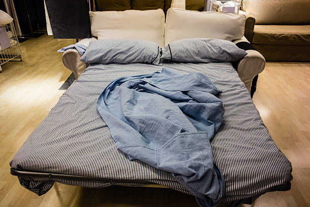 an opened sofa bed with bed clothes and pillows