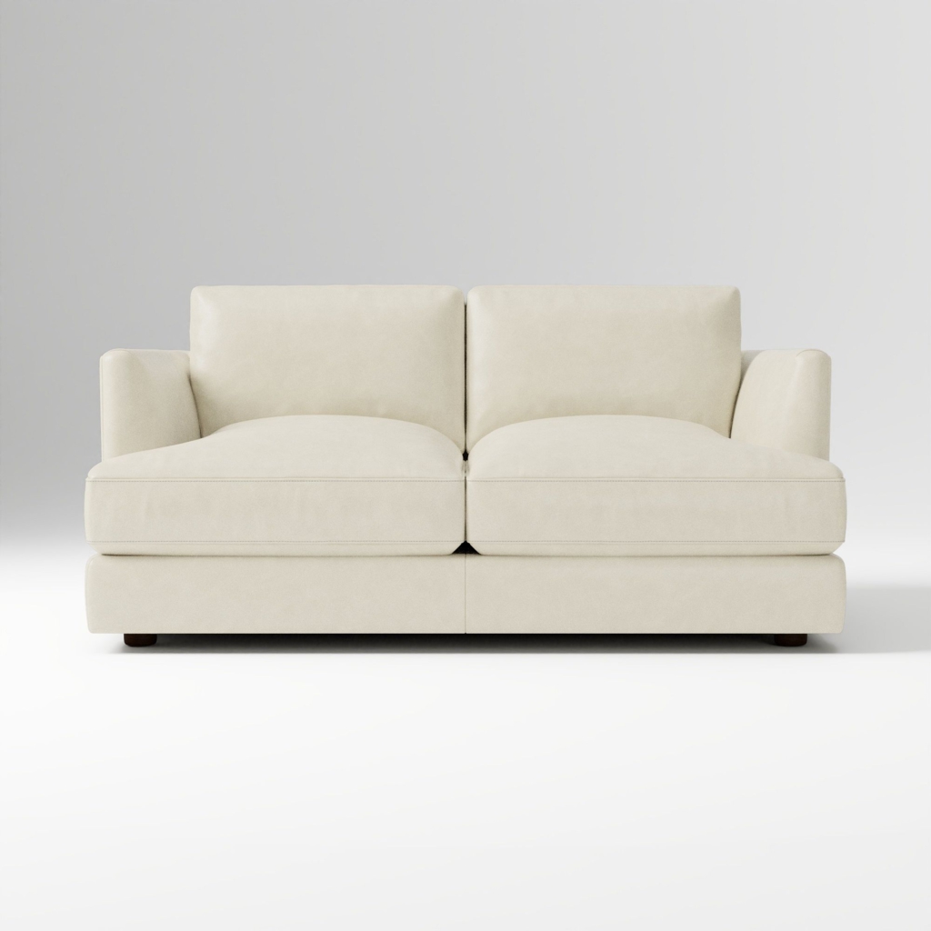 Cream two-seater sofa with plush cushions and slim arms against a light neutral background.