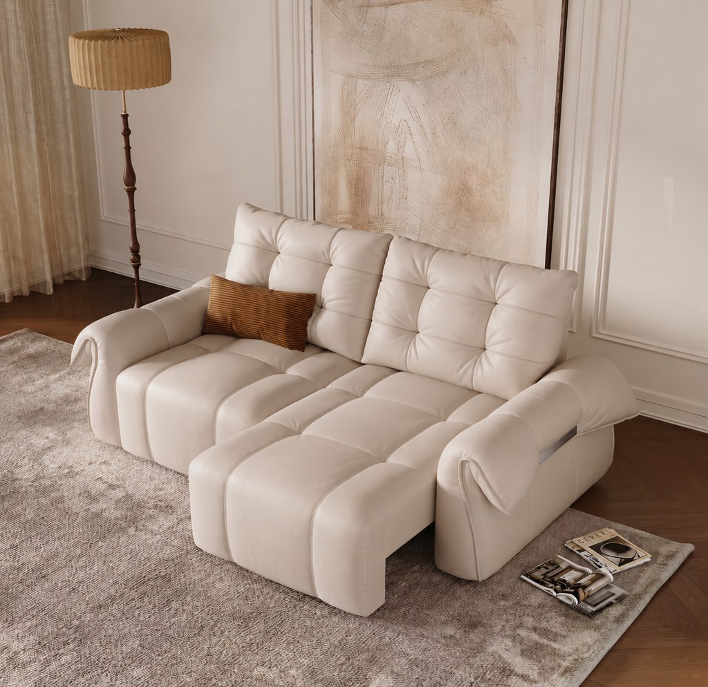 Cream leather sectional sofa with an extended chaise in a warm neutral living room with a floor lamp, abstract wall art, and magazines.