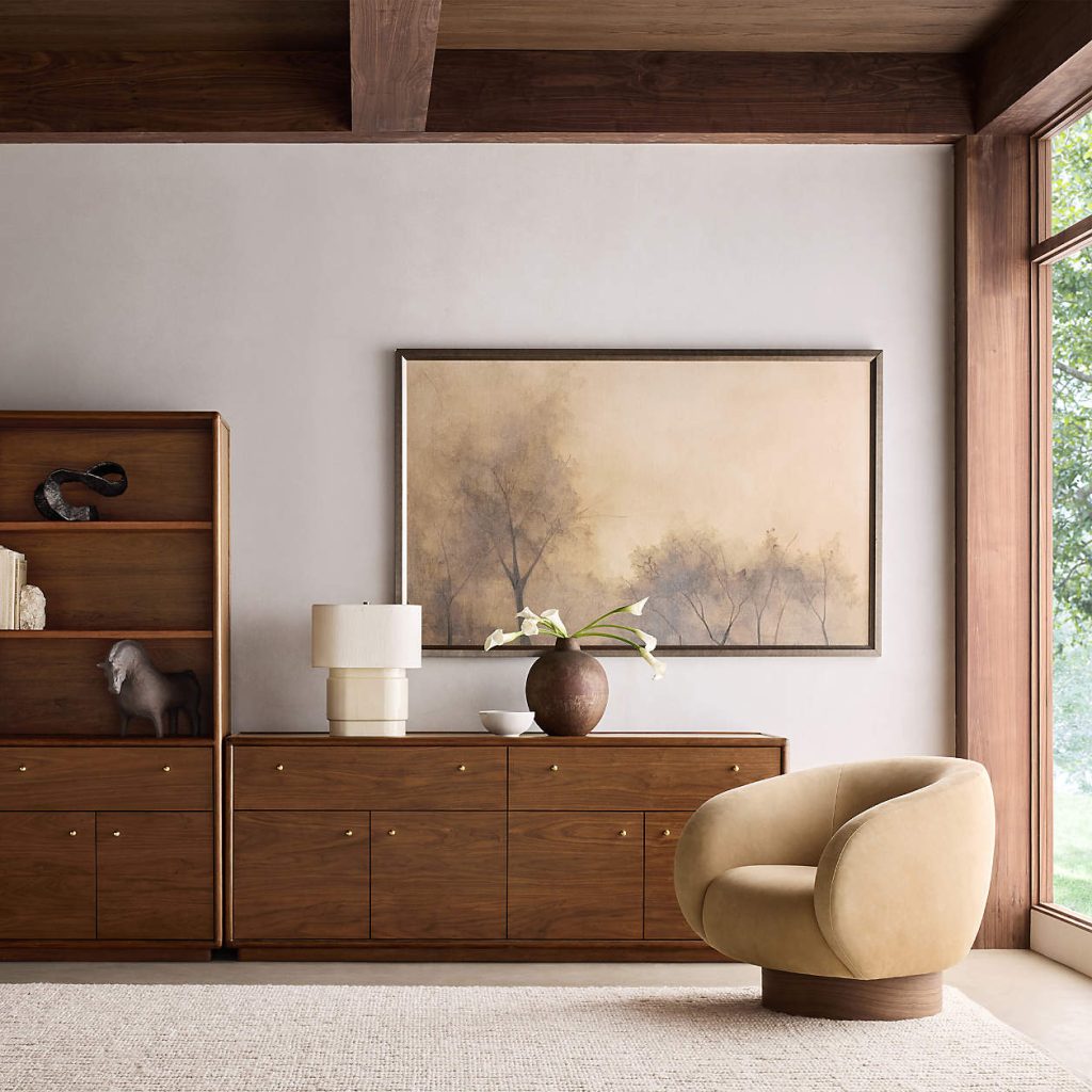 a walnut storage media console with drawers and some decorations on top near a sofa in a bright living room