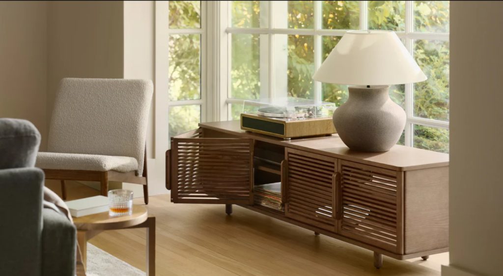 a walnut media console with storage with a lamp on top near a sofa in a small living room or apartment