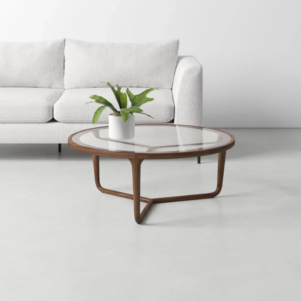a simple-designed and round glass coffee table near a white sofa, with a plant on top