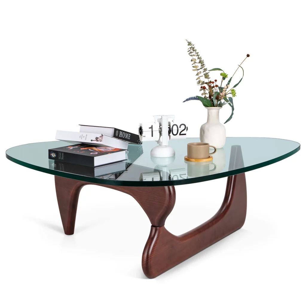 an oval glass coffee table with a clock, a cup, some books and decorations on top