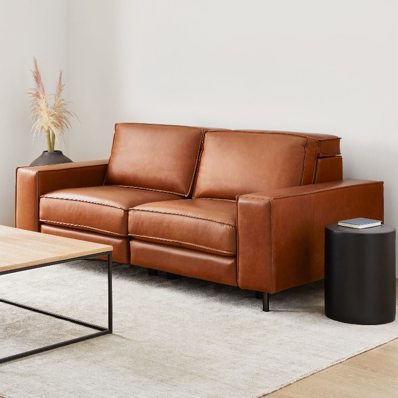a brown leather reclining sofa with square arm near a rectangular coffee table and a black side table in a bright living room