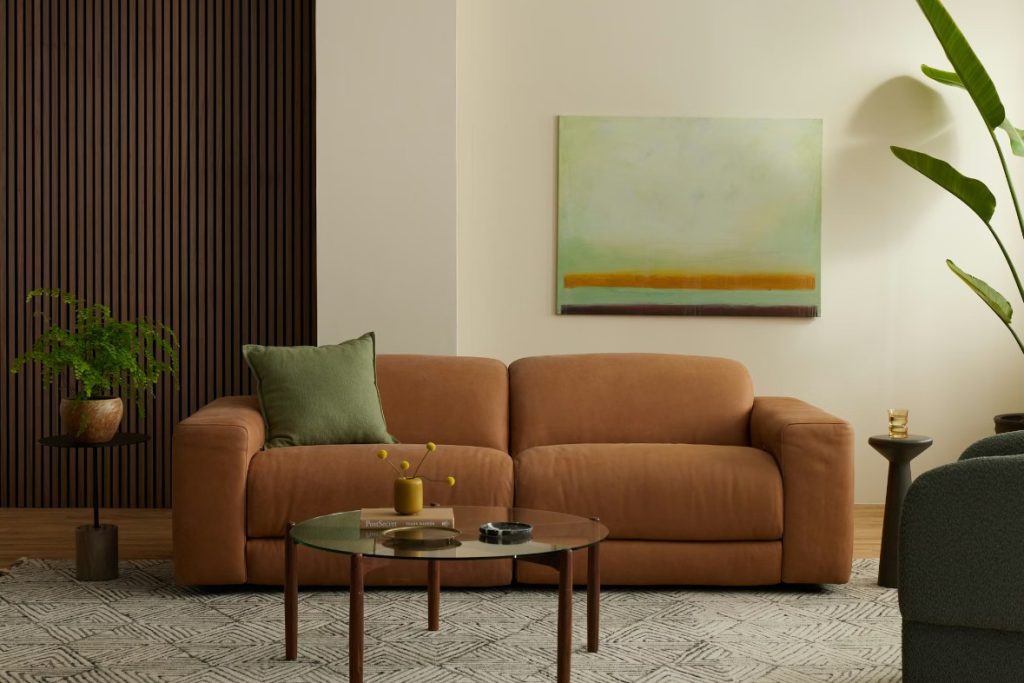 a brown leather modular reclining sofa with a green cushion near a coffee table