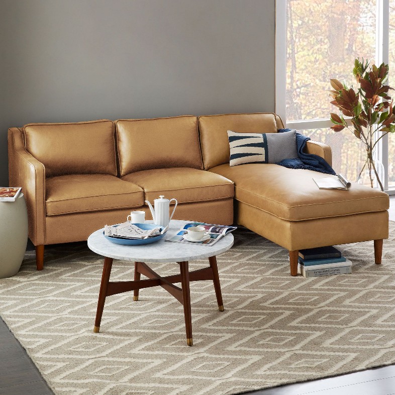 a small leather 2 seat sofa with sectional chaise near a coffee table in a compact living room