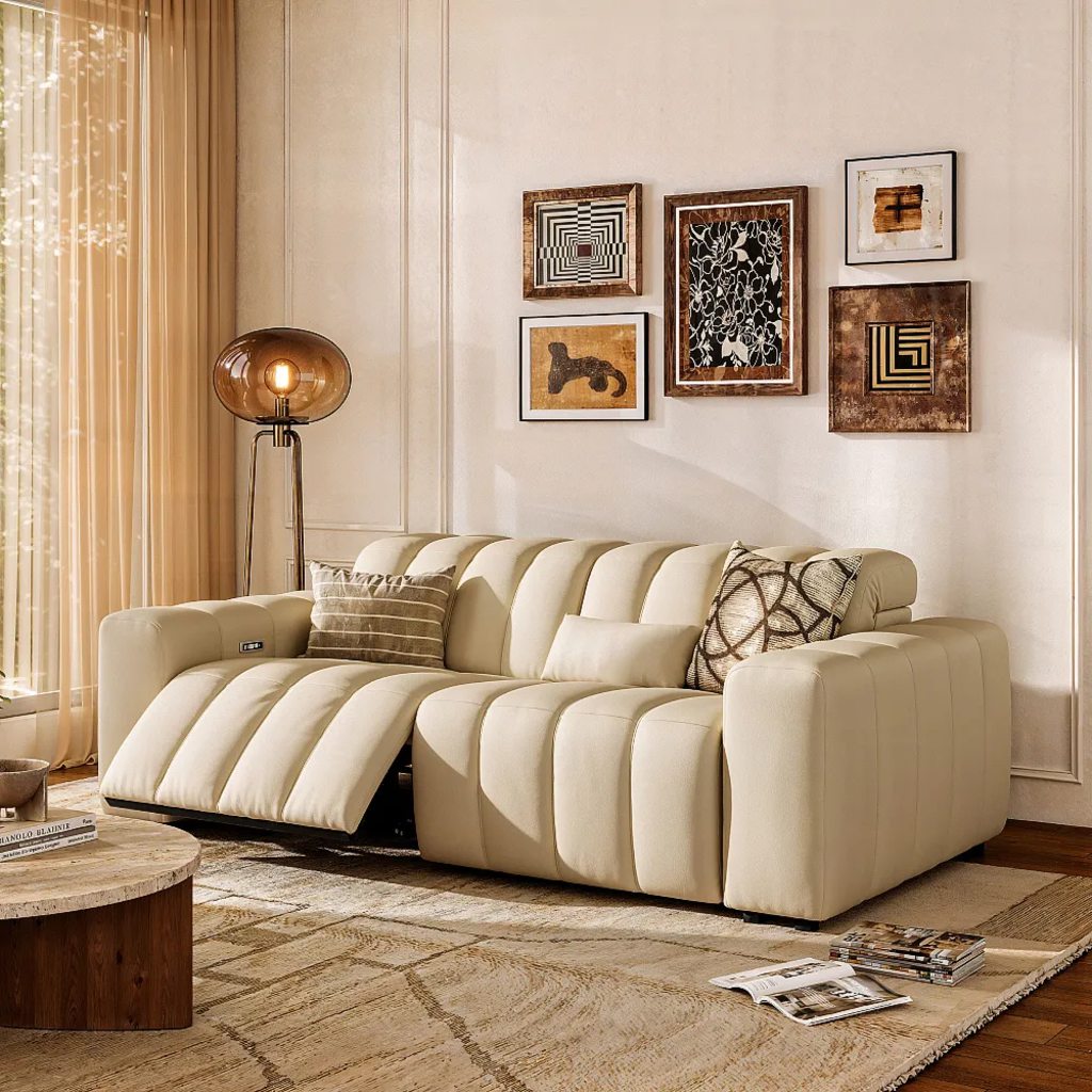 Cream leather power reclining sofa with channel-tufted cushions and one extended footrest in a warm living room.