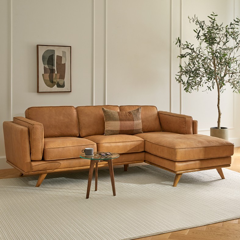 Tan leather L-shaped modular sofa with chaise in a bright modern living room