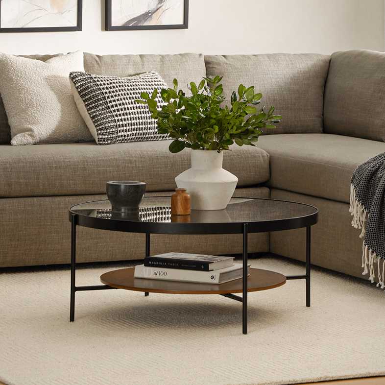 a round and black glass coffee table with flowers and decorations on it