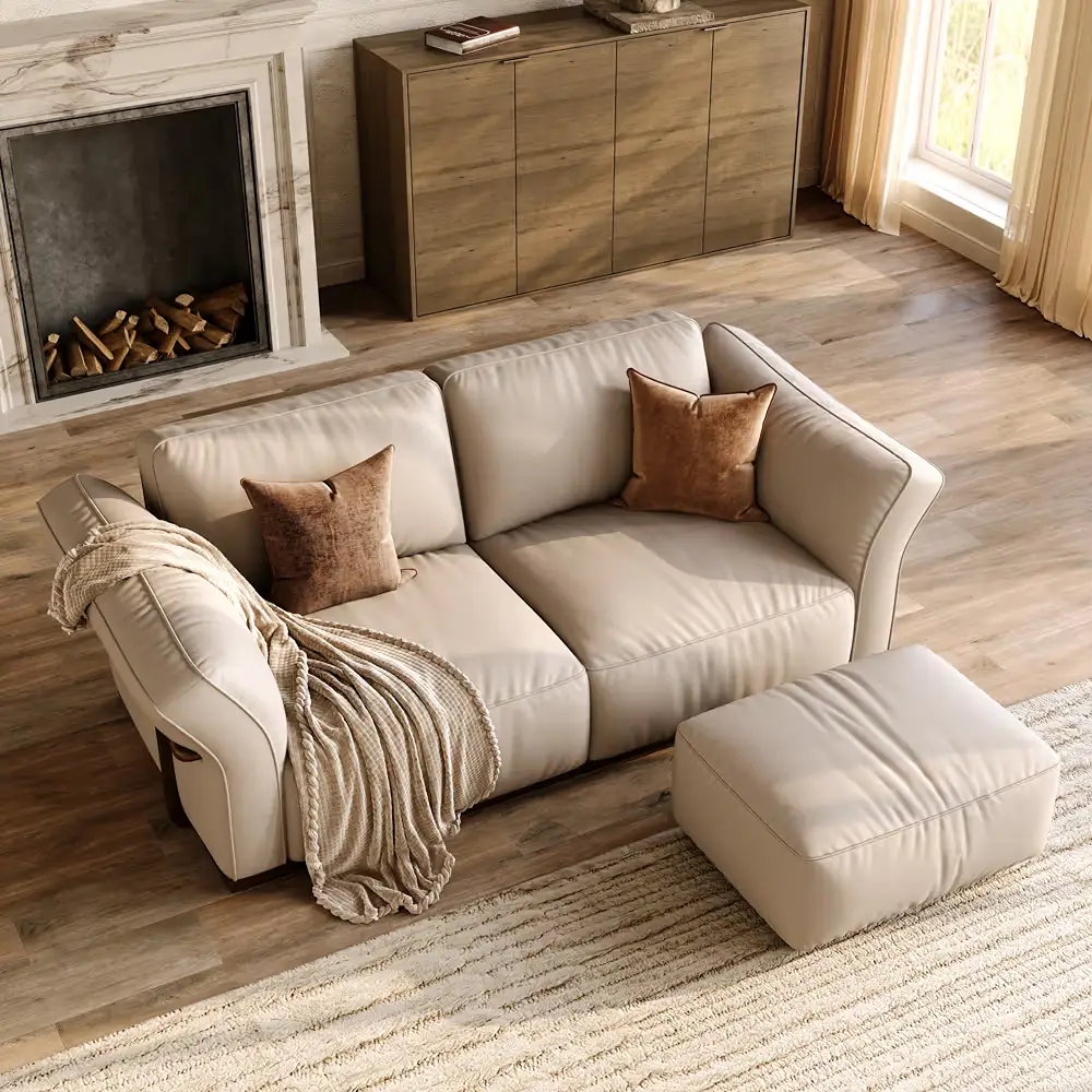 Cream leather loveseat with matching ottoman, brown throw pillows, and a knit blanket in a bright living room with a fireplace.