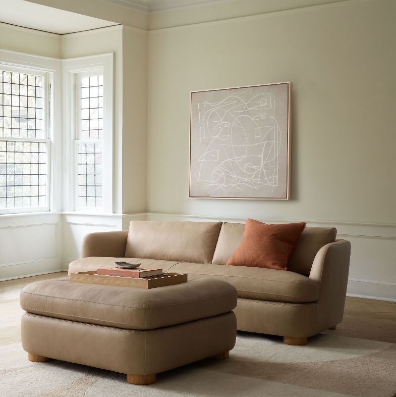 a cream leather sofa with a cushion near a coffee table in a bright living room