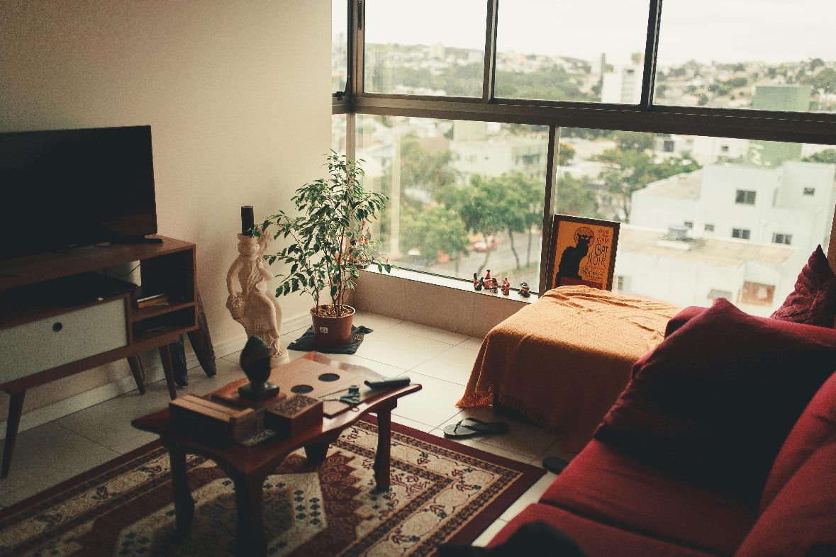 a compact studio apartment with a small tv stand, a wood coffee table and a sofa bed near the window
