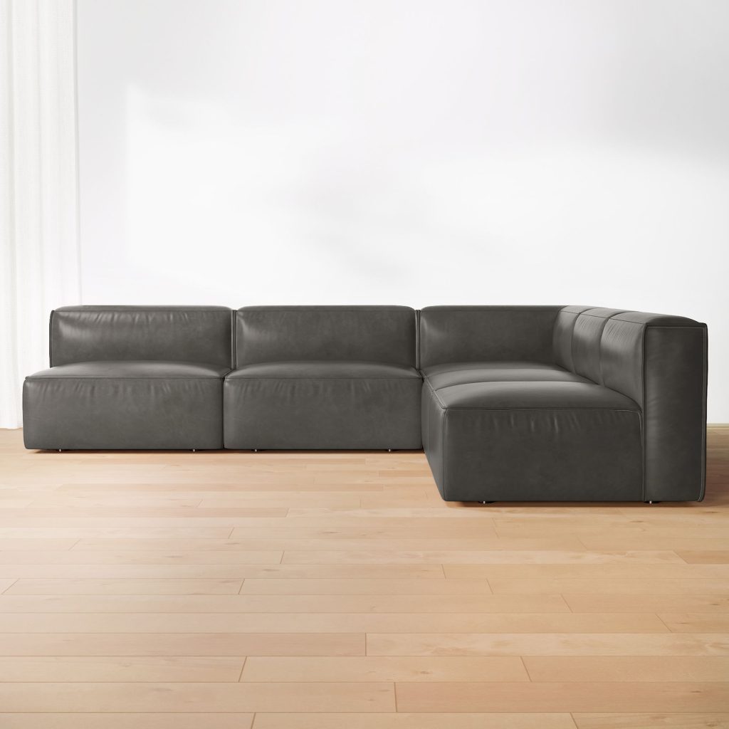 Dark gray leather modular sofa with chaise in an L-shaped sectional layout on a light wood floor