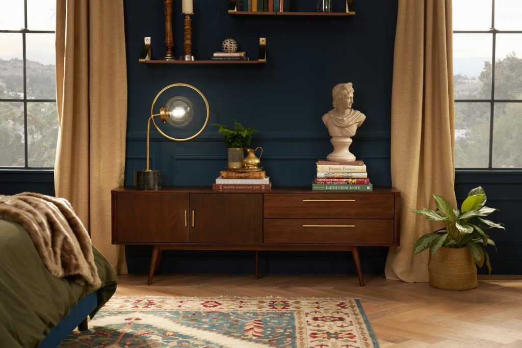 a small minimalism tv stand with drawers and decorations on top near a bed in a small bedroom