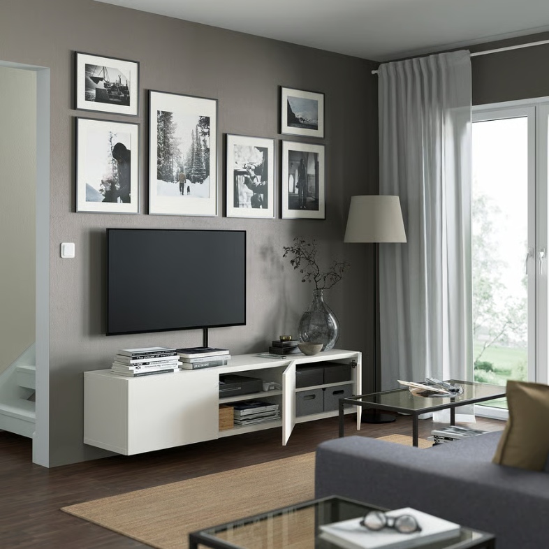 a white media console with three drawers for storage, a tv, some books and decorations on top near against a wall in a modern living room