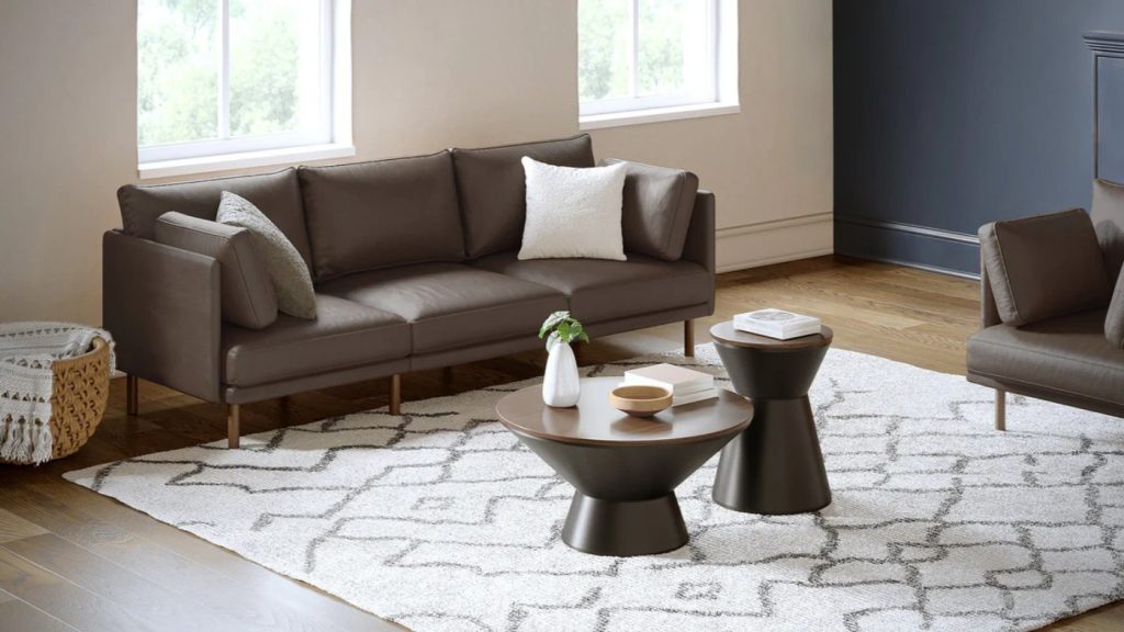 Dark brown leather sofa in a modern living room with tapered legs and a curved back design