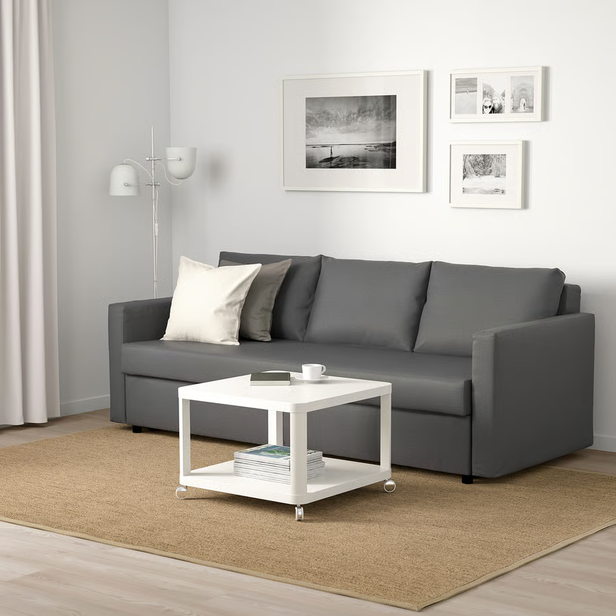 IKEA sleeper sofa with cushions near a small white coffee table in a modern and compact living room