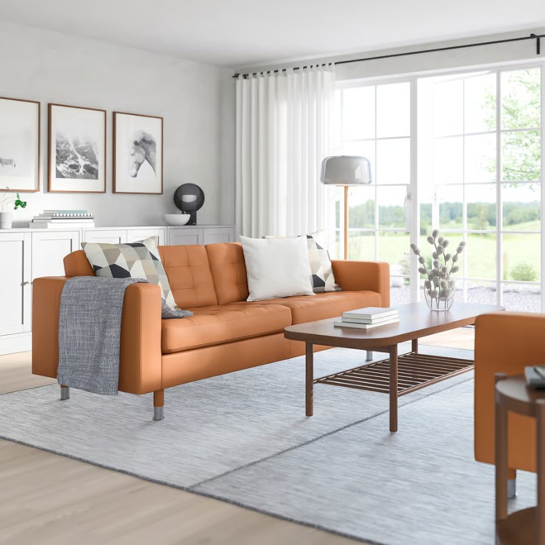a brown 3-seater leather sofa with cushions near a rectangular wood coffee table in a bright and modern living room