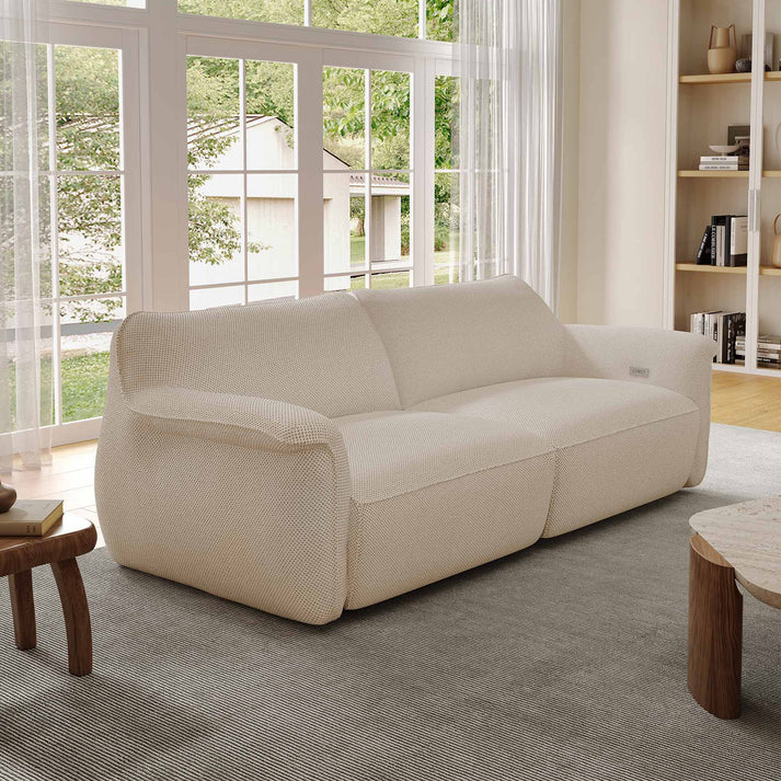 an Eureka Ergonomic Vero Power Sleeper Sofa near a wood coffee table and a wood side table in a bright and modern living room with large window and bookshelf