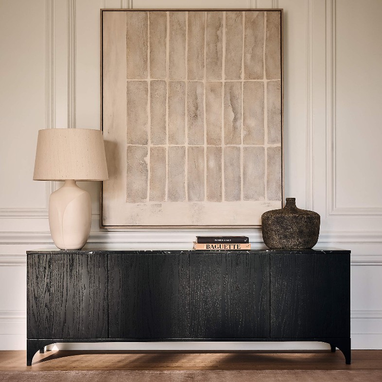 CB2 Roane 80” Black Oak Wood Media Console with a lamp, some books, decorations and a painting on top in a bright and modern living room