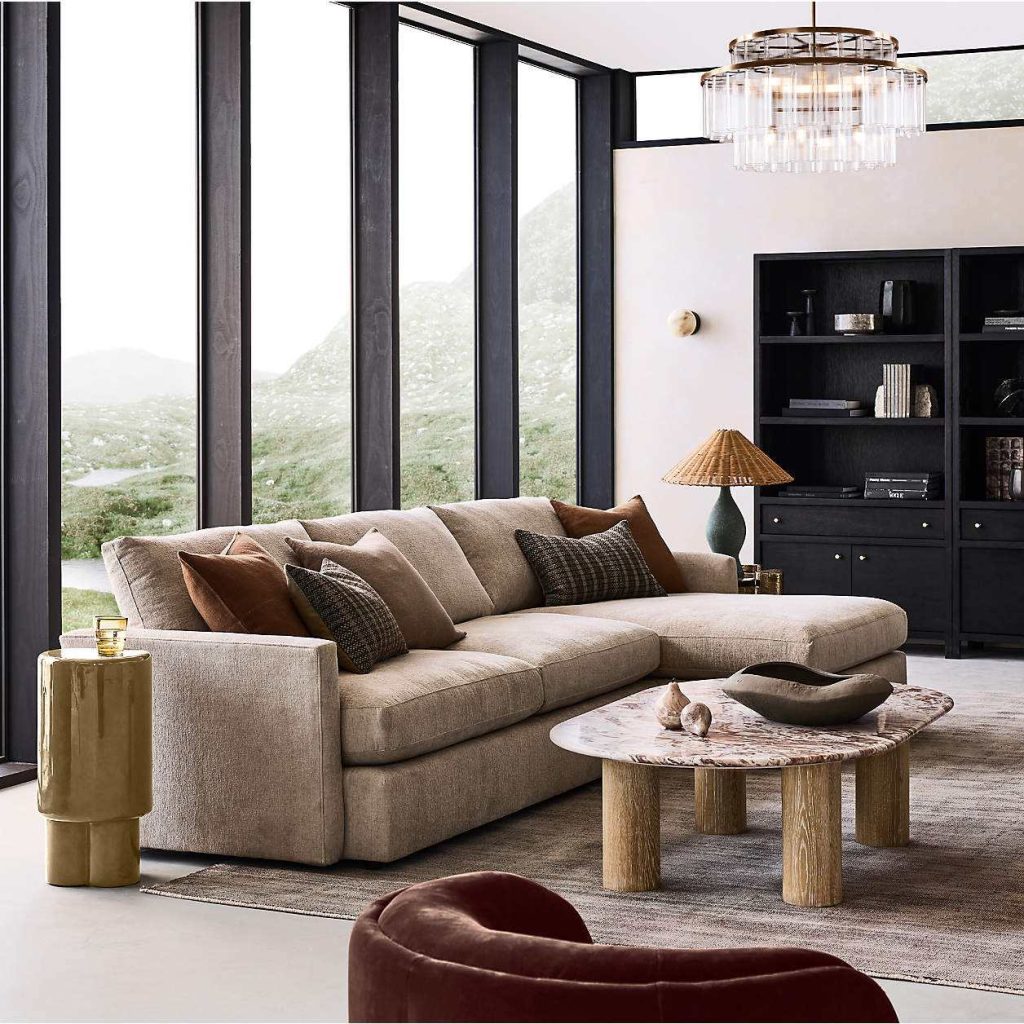 Crate & Barrel Lounge Deep 93" Sofa in low profile near an oval marble coffee table, a side table and a black bookshelf in a modern and bright living room