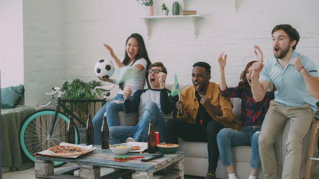 Enthusiastic friends celebrating a soccer game in a cozy living room setting