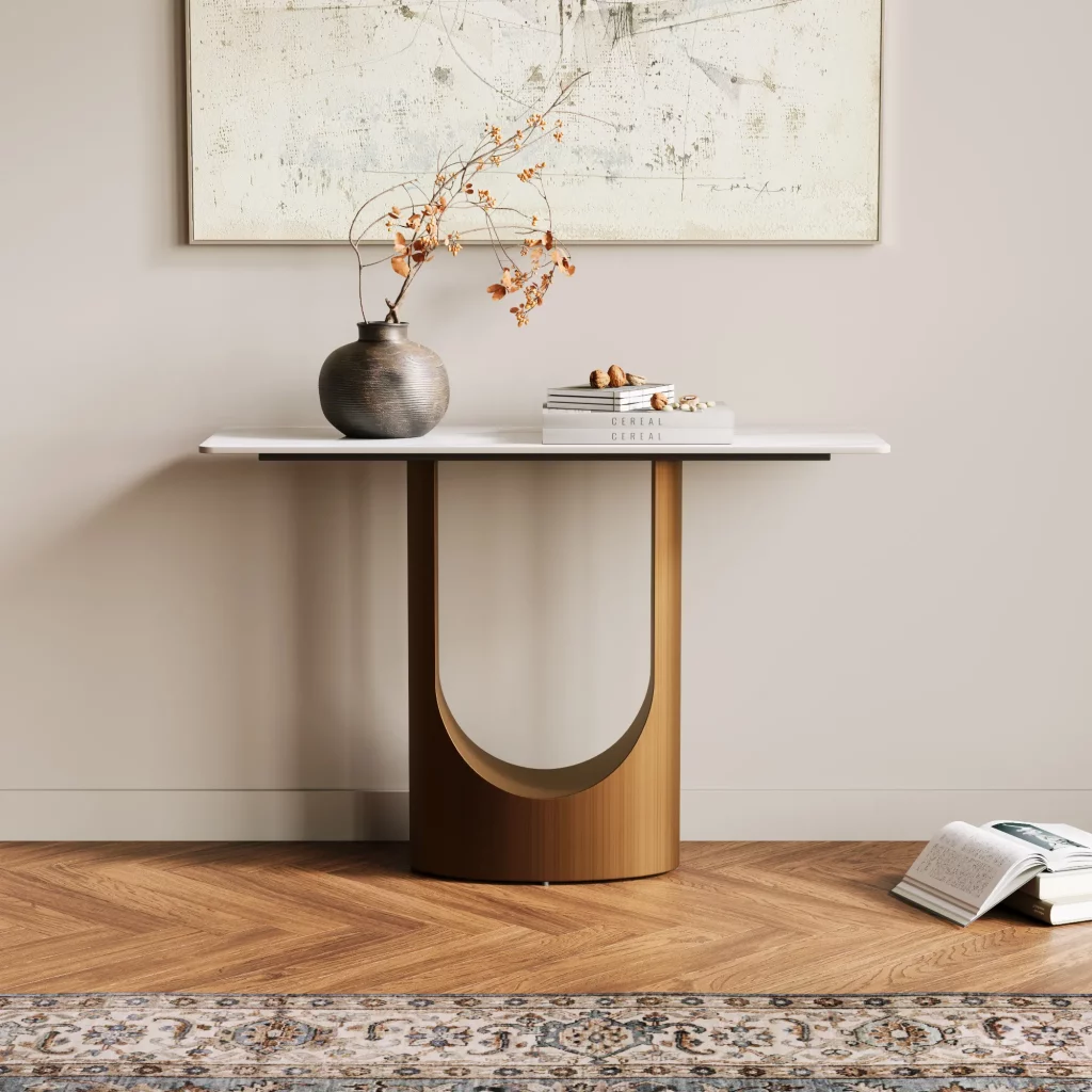 A white and bronze console table placed below a round mirror, styled with a lamp, tray, and simple greenery in a bright entryway.